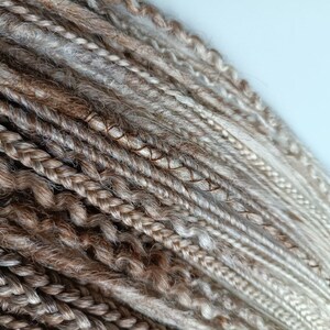 May include: A bundle of brown and blonde synthetic dreadlocks. The dreadlocks are made of kanekalon hair and are ready to be installed.