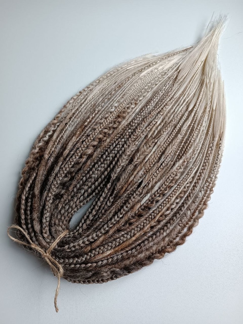 May include: A bundle of brown and blonde ombre synthetic hair extensions. The hair is braided and tied together with a string.