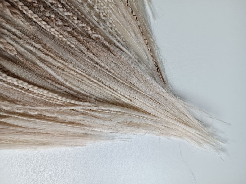 May include: A bundle of blonde and light brown synthetic hair extensions. The hair is long and straight, with a variety of shades of blonde and brown.