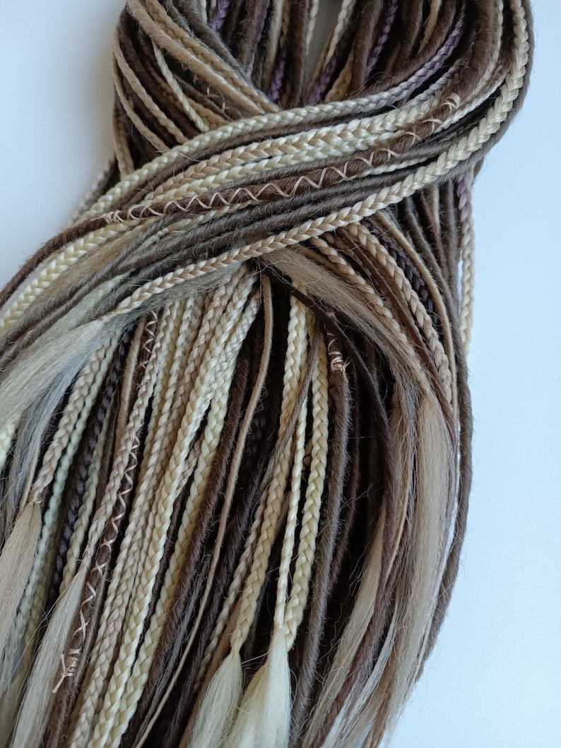 May include: A bundle of brown, beige, and blonde synthetic hair extensions. The extensions are braided and have a variety of textures.