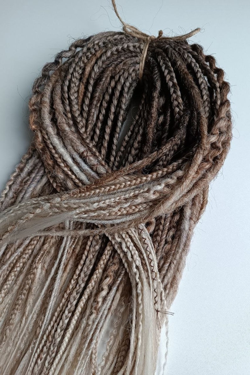 May include: A bundle of brown and blonde synthetic hair extensions. The hair is braided and tied together with a string.