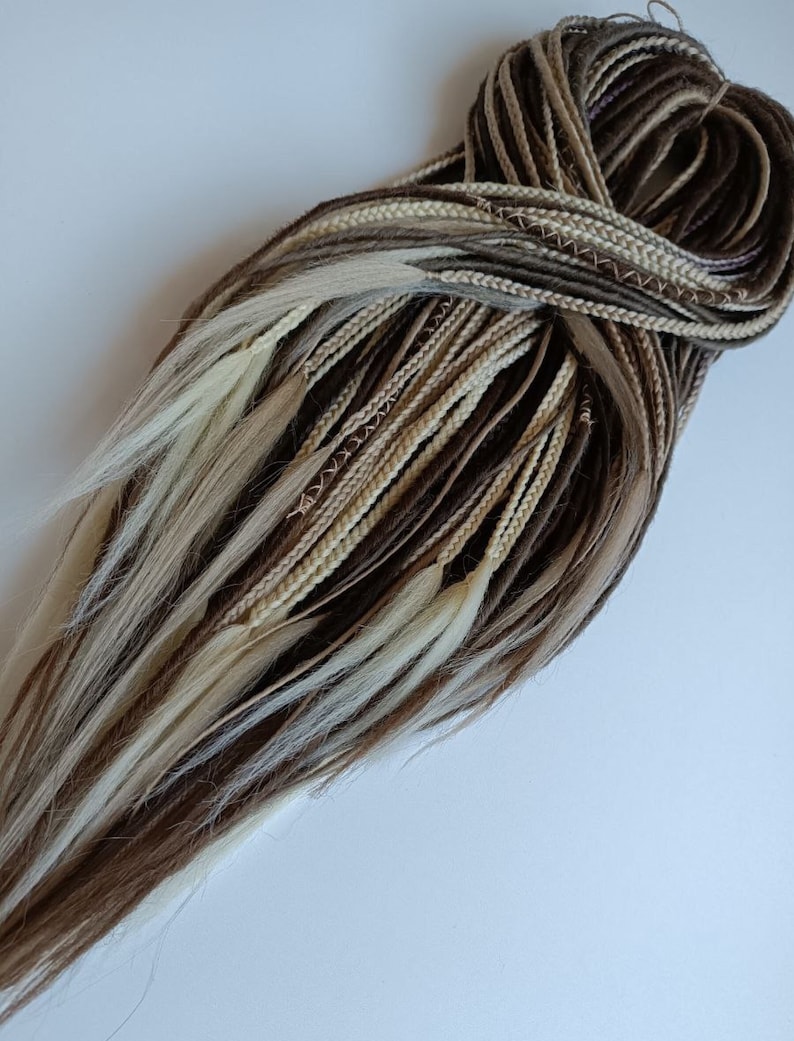 May include: A bundle of brown, beige, and blonde synthetic hair extensions. The hair is braided and tied together at the top.