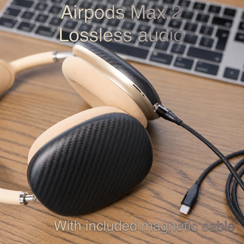 May include: Over-ear headphones featuring beige ear cushions and black carbon fiber-textured outer shells. The text Airpods Max 2 Lossless audio and With included magnetic cable is visible. A black braided magnetic cable is connected to the side.