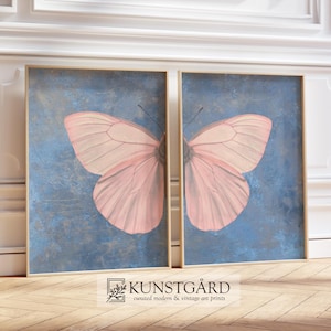 May include: Two framed prints of a pink butterfly on a blue background. The butterfly is centered in each frame and is facing the right. The frames are gold and have a distressed look.