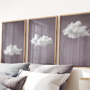 May include: Three framed prints with a light purple background and white clouds. The frames are made of natural wood.