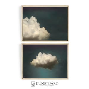 Puede incluir: Dos impresiones enmarcadas de una sola nube blanca sobre un fondo azul oscuro. La impresión superior muestra la nube en el lado izquierdo del marco, mientras que la impresión inferior muestra la nube en el centro del marco. Las impresiones están enmarcadas en oro.