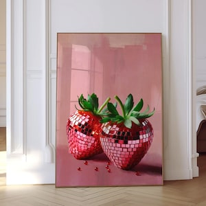 May include: Two red strawberries with a disco ball design on a pink background. The strawberries are in focus and the background is blurred.