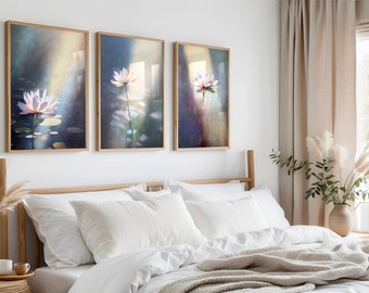 Könnte beinhalten: Drei gerahmte Drucke von Aquarellmalereien von rosa Lotusblumen mit grünen Blättern und Wasserreflexionen. Die Drucke hängen an einer weißen Wand über einem Bett mit weißen Bettwäsche und einer beigefarbenen Wolldecke.