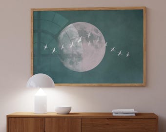 May include: A framed art print featuring a large, two-toned moon against a teal background. White birds fly across the moon's surface. The artwork is displayed above a wooden cabinet with a white lamp and bowl.