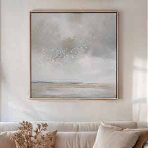 May include: A square framed wall art piece featuring an abstract landscape painting. The composition displays a cloudy, muted grey sky above a soft beige horizon line. A flock of small white birds is depicted in flight across the centre.