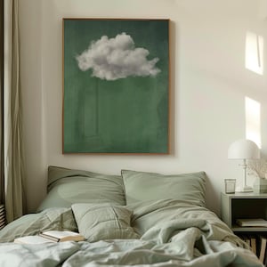 May include: A framed print of a single white cloud against a green background. The print is hanging on a white wall above a green bed with white pillows.