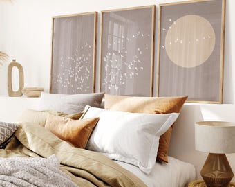 Puede incluir: Tres impresiones enmarcadas con un diseño minimalista que presenta una bandada de pájaros sobre un fondo marrón claro. Las impresiones están colgadas sobre una cama con una funda nórdica de lino beige y una almohada blanca.