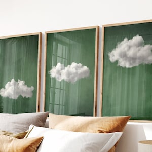 May include: Three framed prints with a green background and white clouds. The clouds are different sizes and shapes. The frames are a light wood color.