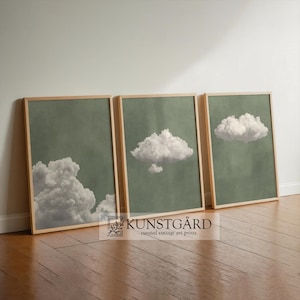 Puede incluir: Tres impresiones artísticas enmarcadas con imágenes de nubes. Cada impresión tiene un marco de madera marrón claro y un fondo verde apagado. Las nubes son blancas y esponjosas, con formas y tamaños variados. El texto "KUNSTGÅRD curated vintage art prints" es visible.