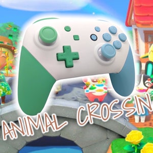 May include: A green and blue Nintendo Switch controller with the text "ANIMAL CROSSING" in brown letters. The controller is in front of a video game scene with cartoon characters.