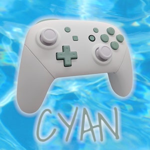May include: A white gaming controller with light blue buttons and a cyan text overlay that says "CYAN".