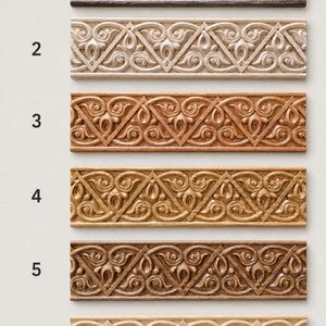 Pu&ograve; includere: Sei modanature rettangolari in legno disposte verticalmente, etichettate da 1 a 5 e Unpainted. Ogni pezzo presenta un identico motivo a volute intagliato. Le finiture variano dal marrone scuro, beige chiaro e rovere al legno naturale.