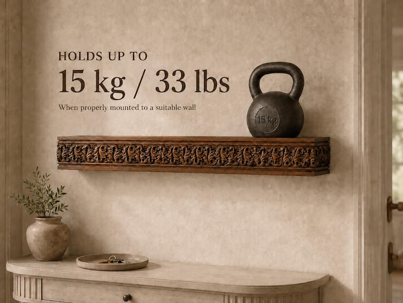 Pu&ograve; includere: Una mensola da parete in legno marrone scuro con intricati motivi floreali intagliati sul bordo anteriore. Il testo sulla parete recita: HOLDS UP TO 15 kg / 33 lbs When properly mounted to a suitable wall. Una kettlebell nera da 15 kg &egrave; appoggiata sopra.