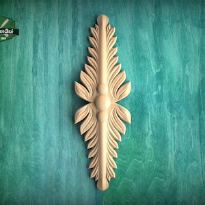 May include: A light-colored wooden decorative applique featuring a symmetrical vertical design with carved leaf-like patterns and three central circular spheres. The piece is elongated and pointed at both ends, displaying detailed wood grain textures.