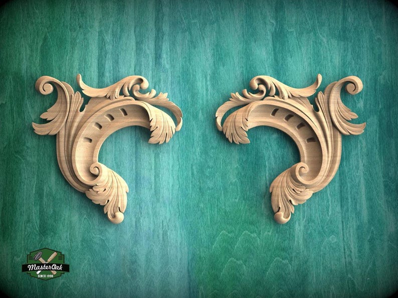 two ornate wooden carvings with intricate scrollwork and floral designs, set against a teal-colored background.