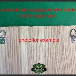Op de afbeelding: De achterkant van een houten bord met twee metalen haken om op te hangen. Het bord is gemaakt van licht hout met een houtnerfpatroon. De tekst "Master Oak Since 1950" is onderaan het bord gedrukt.