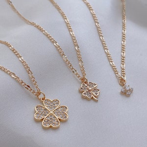 May include: Three gold necklaces with four-leaf clover pendants. The pendants are adorned with sparkling clear rhinestones.