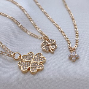 May include: Three gold necklaces with four-leaf clover pendants adorned with clear cubic zirconia stones. The necklaces feature different chain styles.