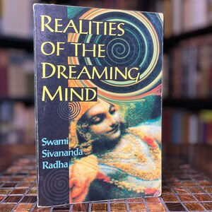 May include: A book titled "Realities of the Dreaming Mind" by Swami Sivananda Radha. The cover features a colorful illustration of a woman with a swirling background.