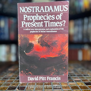 Peut inclure: Un livre de poche intitulé Nostradamus Prophecies of Present Times? A radical new interpretation and explanation of the prophecies of Michel Nostradamus par David Pitt Francis. La couverture présente une illustration de paysage abstrait sombre et ardent.