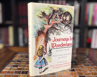 May include: A vintage hardback book titled "Journeys in Wonderland" by Lewis Carroll with illustrations by John Tenniel. The cover features a colourful illustration of Alice standing in a forest with a Cheshire Cat in a tree.