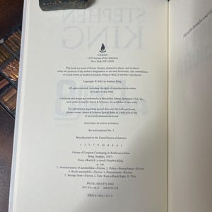 Może przedstawiać: Otwarta książka z tekstem z powieści Stephena Kinga, "From a Buick 8". Strona zawiera informacje o prawach autorskich, dane wydawcy i dane Biblioteki Kongresu. Książka jest otwarta na stronie z tekstem i dekoracyjnym ogranicznikiem do książek.