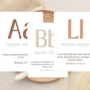 Può includere: Tre carte bianche con lettere marroni e disegni floreali. Ogni carta presenta una lettera diversa e un versetto biblico. La prima carta ha la lettera "A" e il versetto "Perché tutti hanno peccato e sono privi della gloria di Dio." Romani 3.23. La seconda carta ha la lettera "B" e il versetto "Siate invece benevoli gli uni con gli altri, teneri e misericordiosi, perdonandovi a vicenda, come anche Dio vi ha perdonato in Cristo." Efesini 4.32. La terza carta ha le lettere "LI" e il versetto "Ama il Signore Dio tuo con tutto il tuo cuore, con tutta la tua anima e con tutta la tua forza." Deuteronomio 6.5.