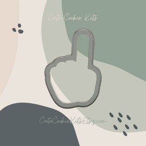 May include: A silver cookie cutter shaped like a hand with the index finger pointing upwards. The cutter is set against a background of abstract shapes in shades of green, beige, and grey.