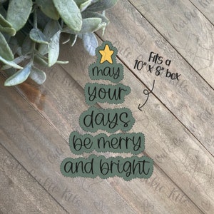 May include: A green Christmas tree-shaped sign with the text "May your days be merry and bright". The sign is on a wood background and fits a 10" x 8" box.