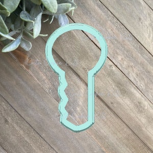 Op de afbeelding: Een lichtblauwe plastic koekjesvormer in de vorm van een sleutel.