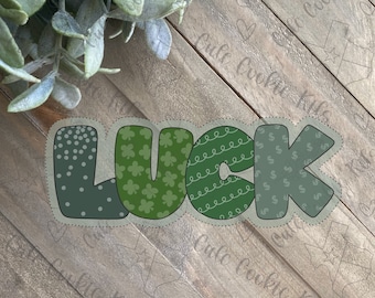 Könnte beinhalten: Ein grünes und weißes "LUCK"-Schild mit verschiedenen Mustern auf jedem Buchstaben. Die Buchstaben sind schwarz umrandet und haben einen gepunkteten Rand.