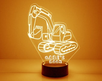 May include: A white acrylic night light shaped like an excavator with the words "Gabe's Room" underneath. The light is on and illuminating the room.