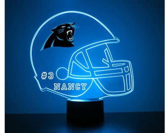 May include: A blue and white 3D printed night light shaped like a football helmet with a Carolina Panthers logo and the name "NANCY" and the number "#3" on the side.