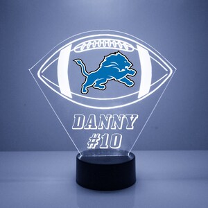 May include: A white acrylic football night light with a blue Detroit Lions logo and the name "DANNY #10" on the base.