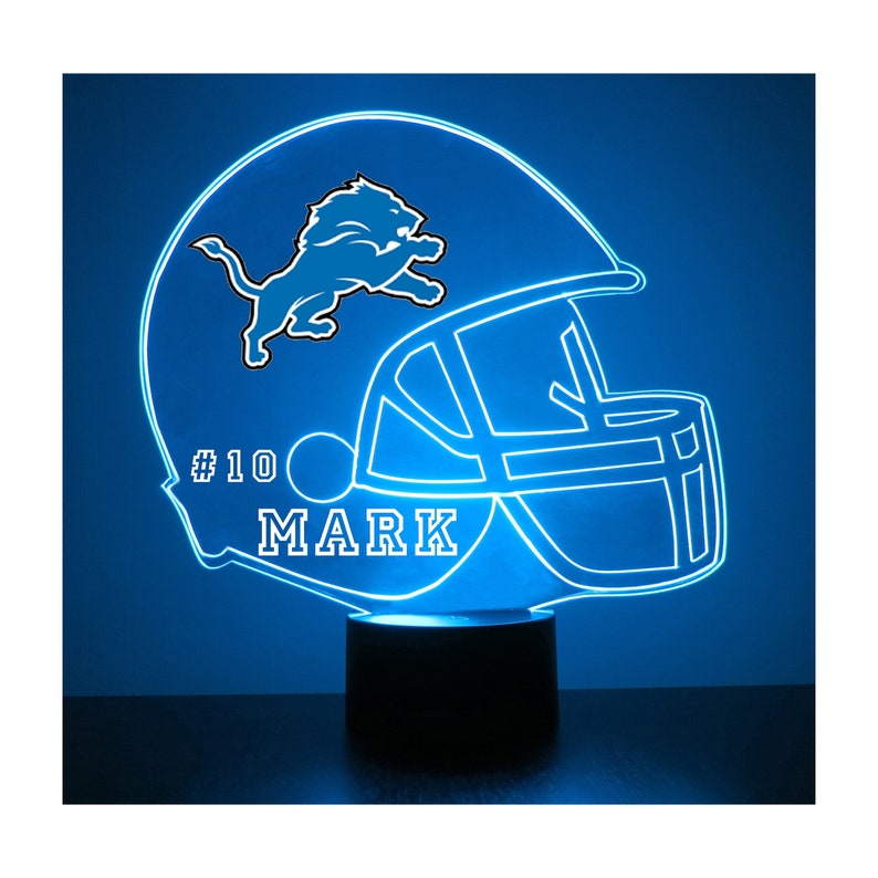 May include: A blue and white 3D printed night light shaped like a football helmet with a Detroit Lions logo and the text "#10 MARK" on the side.