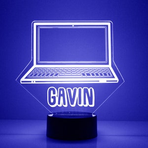 May include: White laptop night light with the name "Gavin" on the base. The light is on a black base.