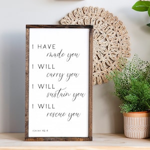 May include: A wooden sign with a white background and black text. The text reads "I HAVE made you I WILL carry you I WILL sustain you I WILL rescue you ISAIAH 46:4".
