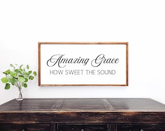 Puede incluir: Un letrero enmarcado en madera con el texto "Amazing Grace How Sweet The Sound" en letra cursiva negra.