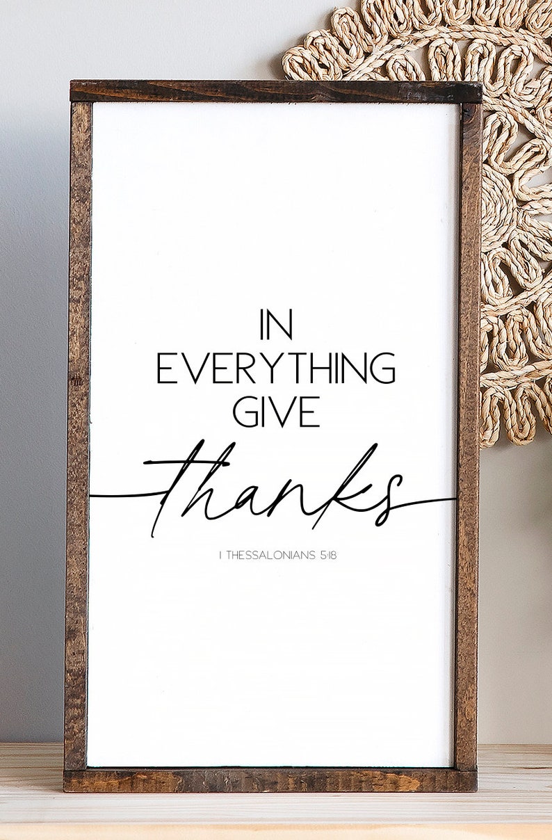 Op de afbeelding: Een wit ingelijst bord met de tekst "IN EVERYTHING GIVE thanks" en de bijbelverwijzing "1 Thessalonicenzen 5:18".