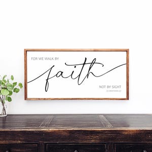May include: A framed wooden sign with the text "For we walk by faith, not by sight. 2 Corinthians 5:7" in black cursive lettering on a white background.