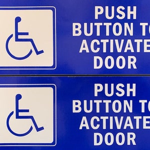 May include: Two blue signs with white text and a wheelchair symbol. The signs read "Push button to activate door".