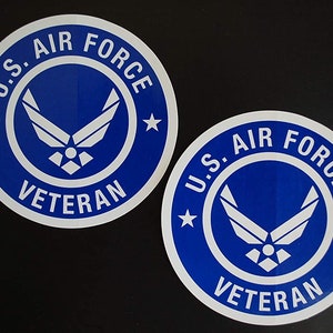May include: Two blue and white round stickers with the words "U.S. Air Force Veteran" and a blue Air Force logo.