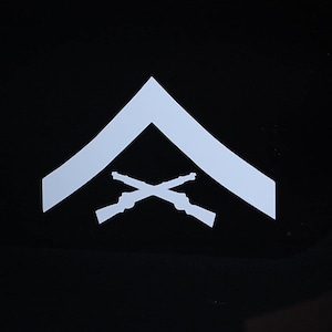 May include: White chevron shaped patch with two crossed rifles in the center.