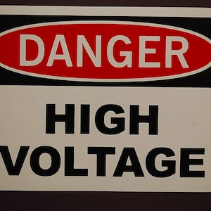 May include: A white sign with black text that reads "DANGER HIGH VOLTAGE" in a red oval with a black border.