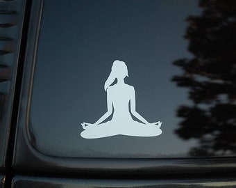 May include: A white silhouette of a person sitting in a yoga pose on a black car window.